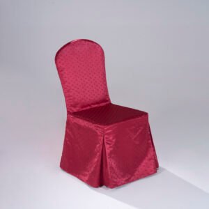 A luxurious burgundy red hotel chair cover with structured corner pleats and a refined polka dot jacquard texture fitted over a banquet chair