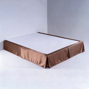 A tailored bronze-brown hotel bed skirt with clean box-pleated corners draped smoothly over a luxury bed base