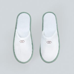 Galaxy Hospitality luxury white closed-toe waffle slippers with plush green piping and custom embroidered emblem on the instep