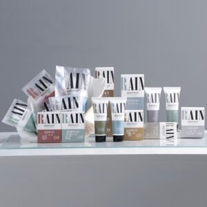 SEVEN PLUS RAIN custom guest room toiletries with bold typography on white and Earth-toned boxes and squeeze tubes in a seashell display tray