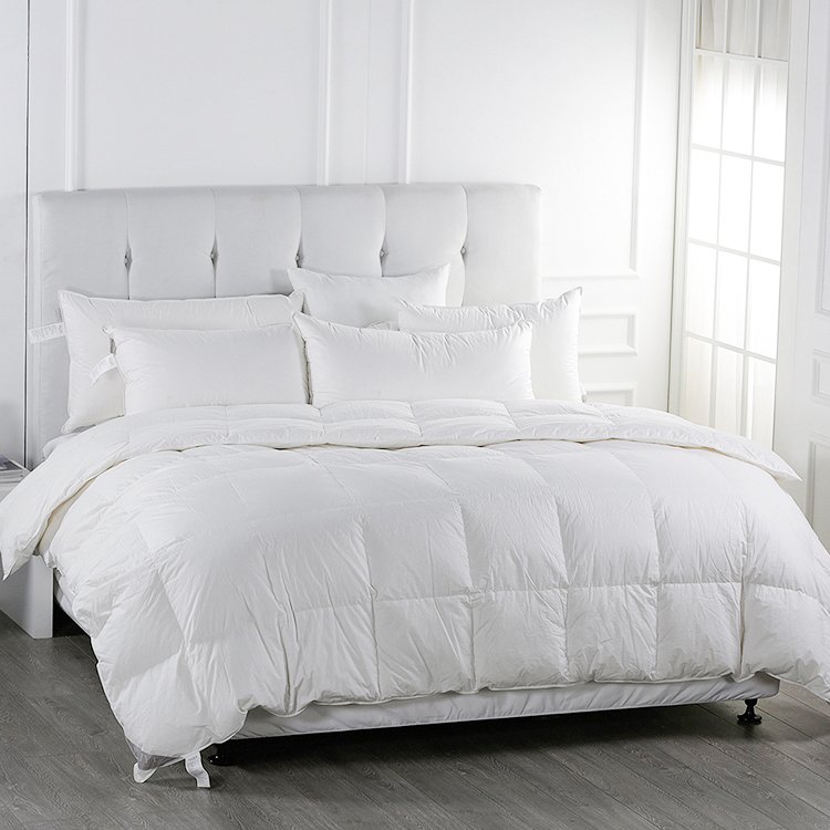 Premium white goose down hotel duvet comforter and matching fluffy pillow inserts on a luxury king-sized bed