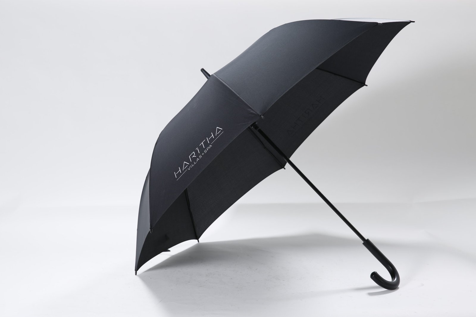 Custom printed black hotel concierge umbrella featuring a comfortable curved handle and white resort logo