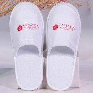 Galaxy Hospitality luxury white closed-toe disposable hotel slippers with red custom embroidered Ramada Beach Hotel logo