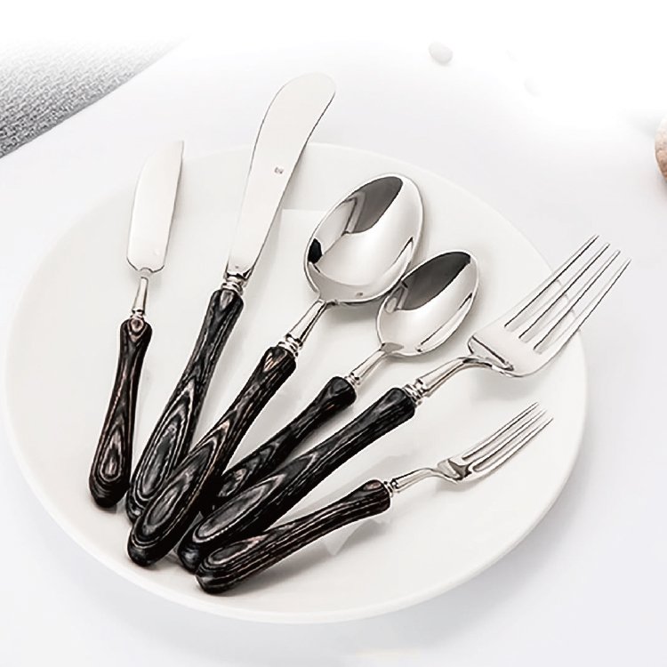 Rustic luxury wood handle cutlery set wholesale items displaying dark wooden grain handles on a white ceramic plate