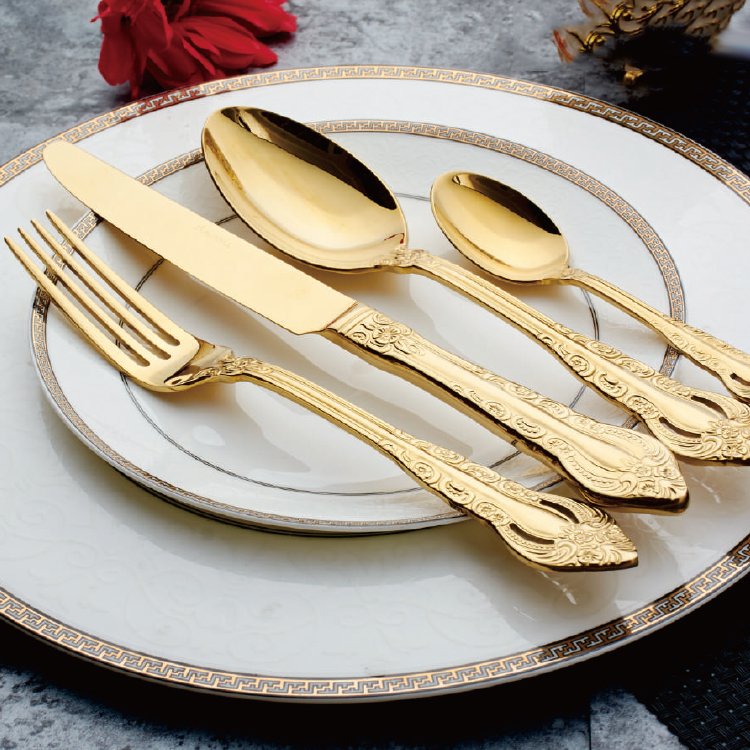 Baroque luxury gold flatware set restaurant cutlery with beautifully engraved handles on a gold rimmed porcelain plate