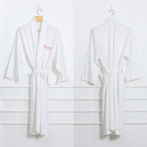 Front and back view of a premium white hotel waffle weave bathrobe featuring a custom red embroidered brand logo on the chest hanging on a wall