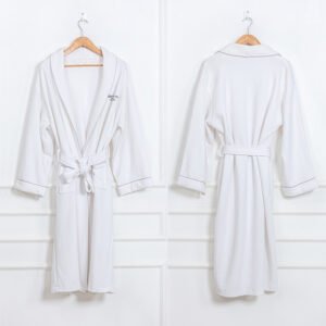 Close-up of a premium white hotel bathrobe with a pineapple waffle weave texture featuring a luxury gold embroidered custom hotel logo on the collar