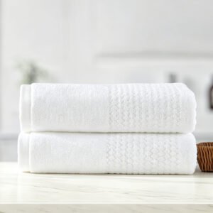 Stacked white luxury hotel towels featuring detailed ribbed striped dobby border weave and woven brand tag