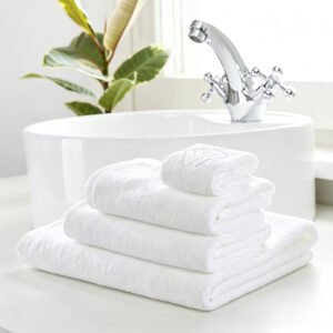 Folded stack of white luxury long-staple cotton hotel bath towels showing woven brand tag and embossed embroidery detail