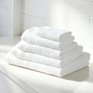 Stacked white luxury hotel towels featuring detailed checkerboard dobby border accents on a clean bathroom vanity