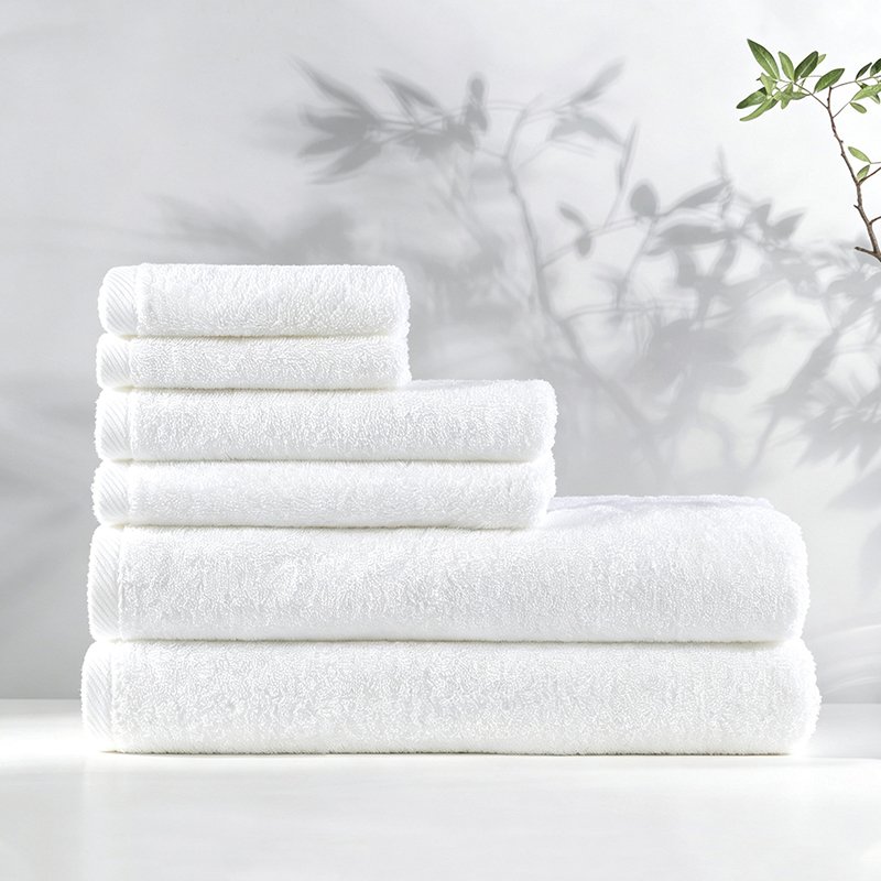Stacked white luxury hotel towels featuring detailed diagonal twill dobby border accents on a spa vanity